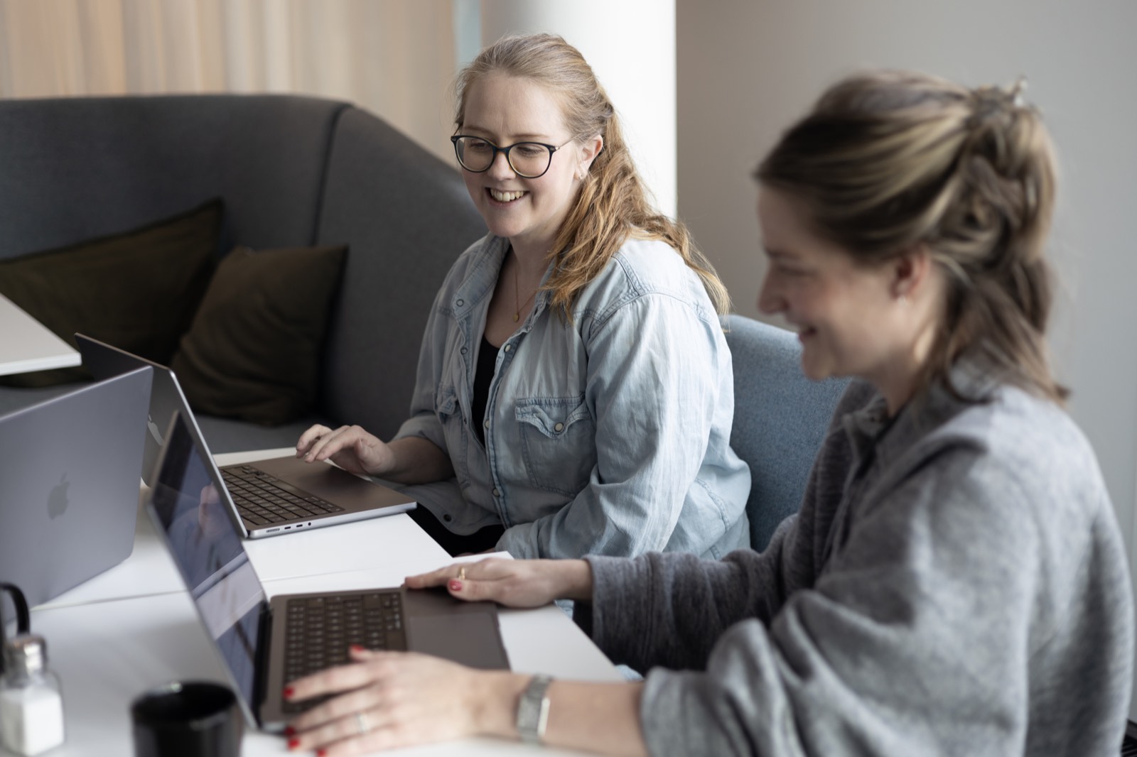 Two colleagues working on laptops at the office